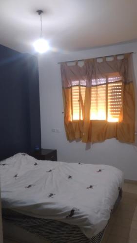 a bedroom with a white bed with a window and a light at בית שיאים באר שבע דירת אירוח in Beer Sheva