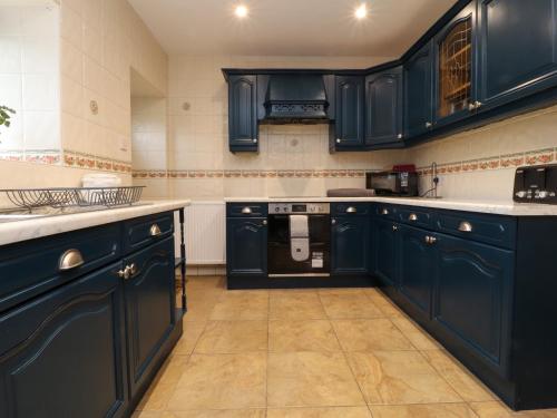 a kitchen with navy blue cabinets and appliances at Popples Barn in Hebden Bridge