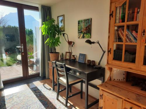 un escritorio con una lámpara y una planta en una habitación en Gallery - Terrasse mit Seeblick und Garten, en Altmünster