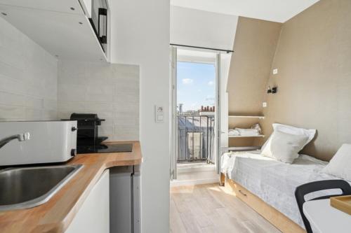- une cuisine avec évier et un lit dans une chambre dans l'établissement 505 Suite Mozart 2 - Cosy studio in Paris 16th, à Paris