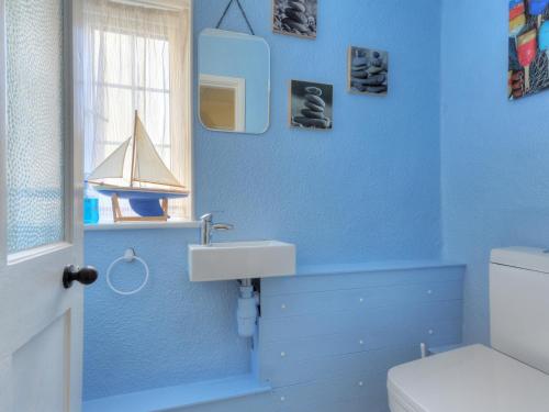 a blue bathroom with a sink and a boat on the wall at 45 Georges Square in Lyme Regis