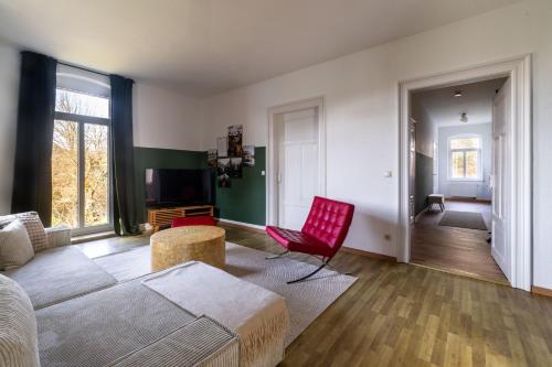 a living room with a bed and a red chair at HohnsteinOase-Fasssauna und Kühlbecken-3 SZ-Parkplatz - Waschmaschine in Hohnstein
