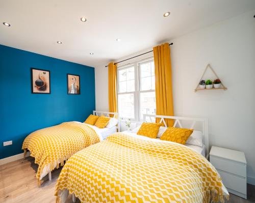 two beds in a room with blue and yellow at Open Mind Property - Hot Tub, 8 Guests & Free Parking in Portsmouth