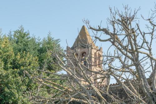 an old building with a tower behind some trees at El Racó de Madremanya - Adults only in Madremanya