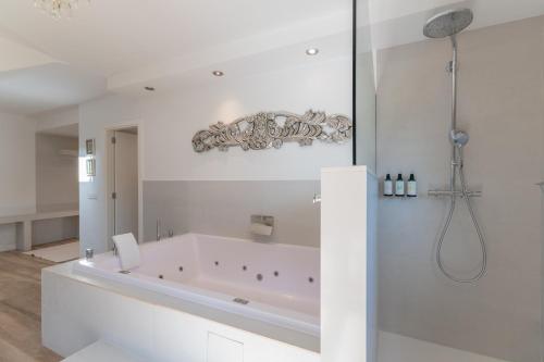 a white bathroom with a tub and a shower at El Racó de Madremanya - Adults only in Madremanya