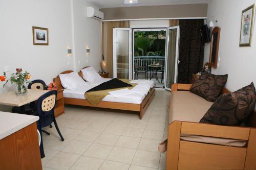 a bedroom with a bed and a couch and a table at Atlon Hotel in Paralia Vrachou