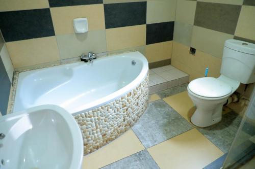 a bathroom with a tub and a toilet and a sink at Yeoville Hotel in Johannesburg