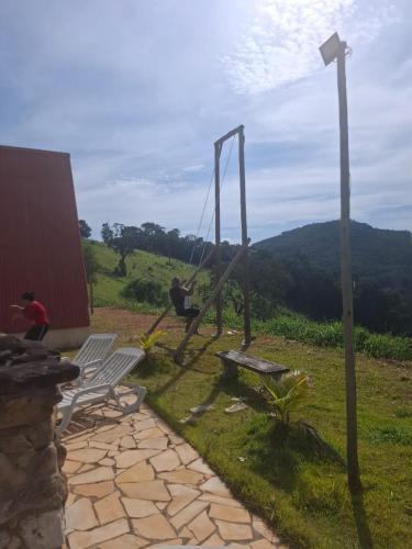 a person sitting on a swing in a yard at Pousada e Camping Tio Wil in Extrema