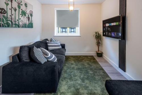 a living room with a black couch and a window at Entire 1 Bedroom Flat Near Bradford Centre and Shipley in Bradford