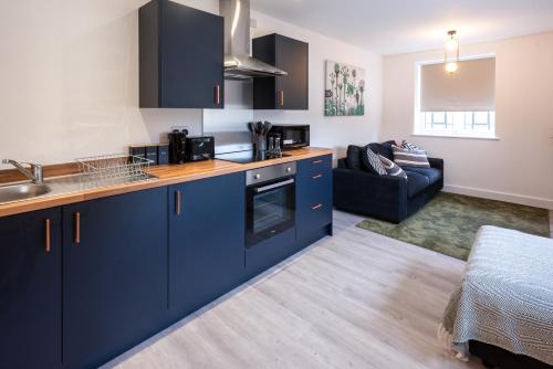 a kitchen with blue cabinets and a living room at Entire 1 Bedroom Flat Near Bradford Centre and Shipley in Bradford