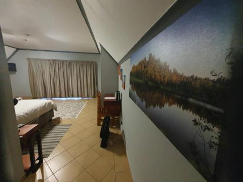 a bedroom with a painting on the wall at Goggas Nest BNB & Restaurant in Matsapha