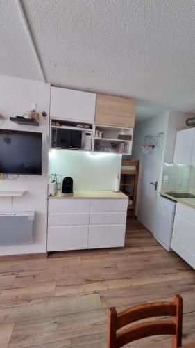 une cuisine avec des placards blancs et une télévision dans la chambre. dans l'établissement P2 au pied des Pistes, à Saint-Étienne-en-Dévoluy