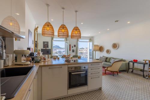 une cuisine avec des lampes suspendues et un salon dans l'établissement Le Classé VIP vue féerique sur le Vieux Port, à La Ciotat