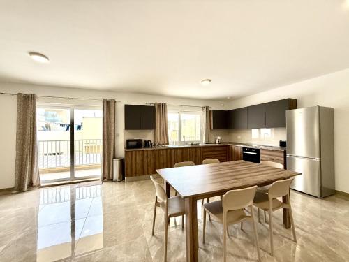 a kitchen with a table and chairs and a refrigerator at New Apartment! Walking distance to the three cities by SF Homes in Tal-Borġ