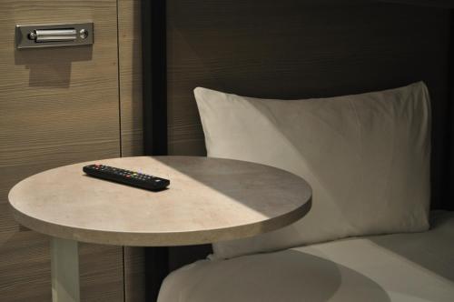 a remote control sitting on a table next to a bed at Heeton Concept Hotel - Kensington London in London