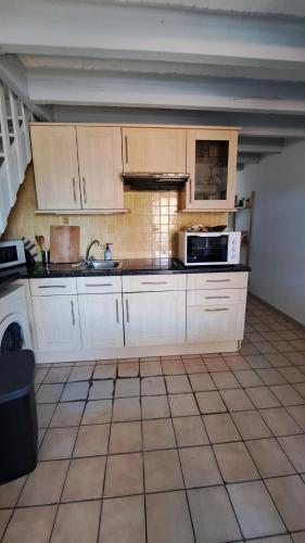 Il comprend une cuisine avec des placards blancs et du carrelage. dans l'établissement Bel appartement face Océan, à Soulac-sur-Mer