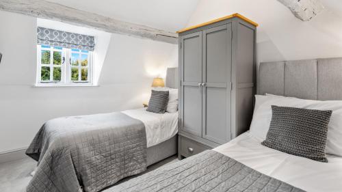 a bedroom with two beds and a cabinet at Vine Cottage in Campden Station