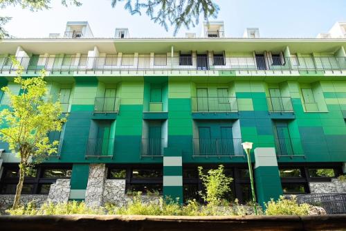 a green building with balconies and trees at Hotel Residence Club Primula in Pescasseroli