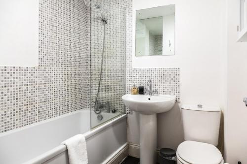 a white bathroom with a sink and a tub and a toilet at Contemporary 2-Bedroom Apartment with 4 Beds, Free Parking, Extended Stay Savings in Birkenhead