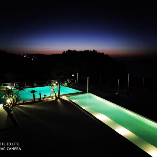 a swimming pool at night with people standing around it at Exceptional Luxury Villa A Masterpiece of Elegance and Comfort in Rafrāf