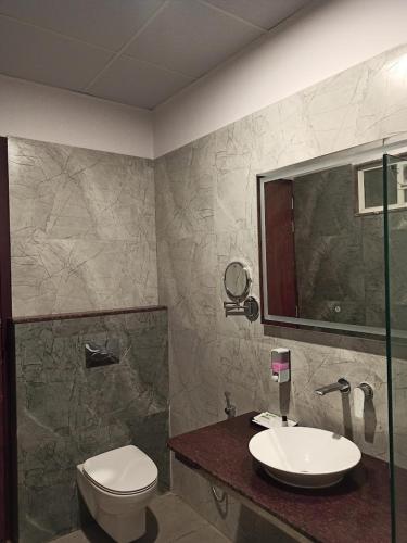 a bathroom with a sink and a toilet and a mirror at Hotel JP Inn in Sītāpur