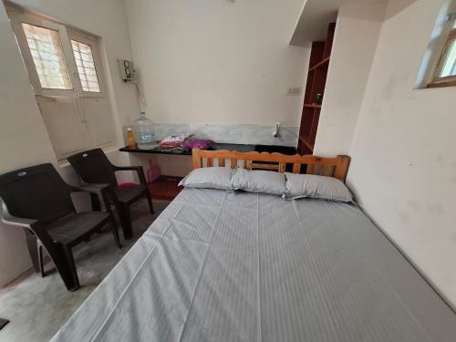 a bed in a room with two chairs and a table at Ashwin Home Stay 2 in Tiruvannāmalai
