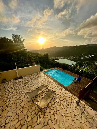 a swimming pool with the sunset in the background at Villa Jamora in Rivière-Pilote