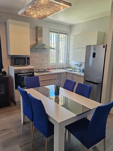 a kitchen with a dining table and blue chairs at Relax & Fun home in Sìnnai