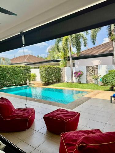 a swimming pool with red chairs in front of a house at Stunning 2-Bedroom Pool Villa in Ban Thalat Choeng Thale