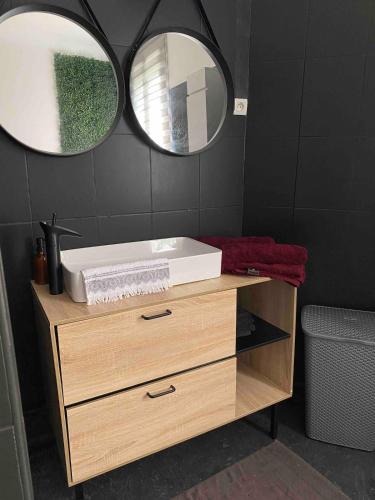a bathroom with a sink and two mirrors at Maison familiale de charme in Solférino