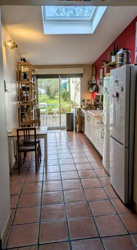 Il comprend une cuisine équipée d'appareils électroménagers blancs, d'une table et d'un réfrigérateur. dans l'établissement Maison Amiénoise, à Amiens