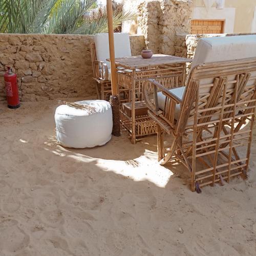a patio with a table and chairs in the sand at Tanirt ecolodge in Siwa