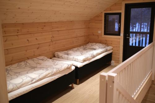 two beds in a room in a wooden cabin at Holiday Village Himmerki in Posio