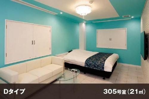 a bedroom with a bed and a couch and blue walls at Hotel Room in Miyazaki