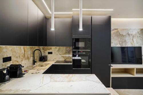 - une cuisine avec des placards noirs et des comptoirs en marbre dans l'établissement 515 Suite Miami - Luxury suite in Paris 6, à Paris