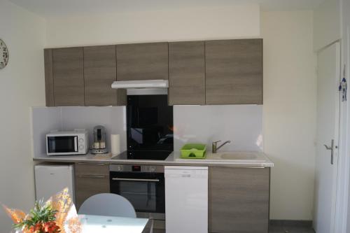 a kitchen with wooden cabinets and a sink and a microwave at Simple Asile in Mers-les-Bains
