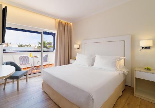 a hotel room with a bed and a balcony at H10 Ocean Dunas - Adults Only in Corralejo