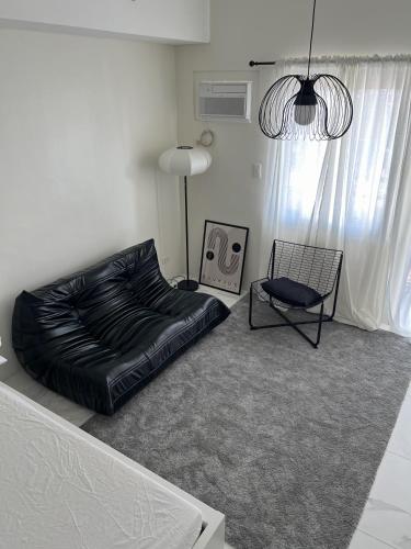 a bedroom with a black bed and a chair at The Bauhouse Studio with Balcony near Eastwood in Manila