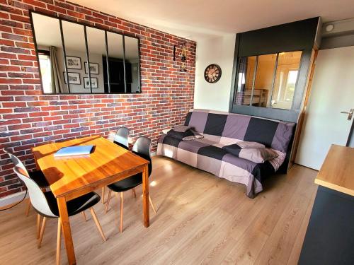 - une chambre avec un lit, une table et un mur en briques dans l'établissement M2M confortable studio cabine avec parking privé gratuit - 4 min à pied de la plage - hypercentre, à Blonville-sur-Mer