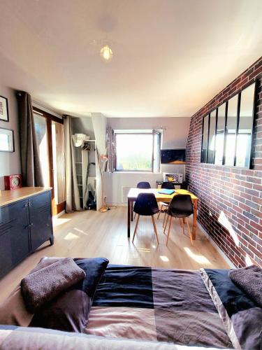 Cette chambre comprend un lit, une table et un mur en briques. dans l'établissement M2M confortable studio cabine avec parking privé gratuit - 4 min à pied de la plage - hypercentre, à Blonville-sur-Mer