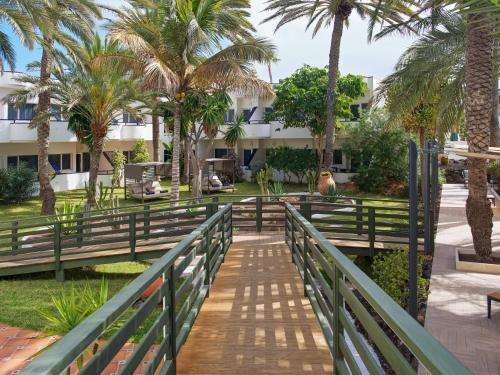 a bridge over a walkway in a park with palm trees at H10 Ocean Dunas - Adults Only in Corralejo