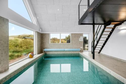 an indoor swimming pool with green tile flooring and a staircase at Dream House With Pool, Whirlpool And Activity Room in Ringkøbing
