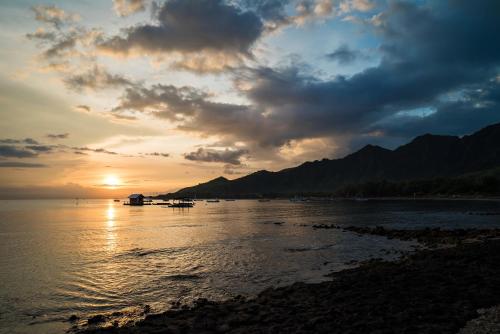 a sunset over a body of water with boats at Taman Sari Bali Resort and Spa in Pemuteran