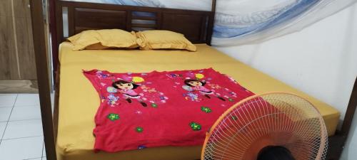 a bed with two dolls on it with a fan at Agus Family Homestay in Labuan Bajo