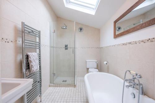 een badkamer met een douche, een bad en een wastafel bij Shrimpers, Southwold in Southwold