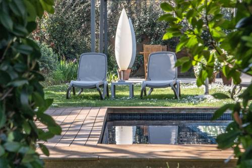 two chairs and a surfboard next to a pool at El Racó de Madremanya - Adults only in Madremanya