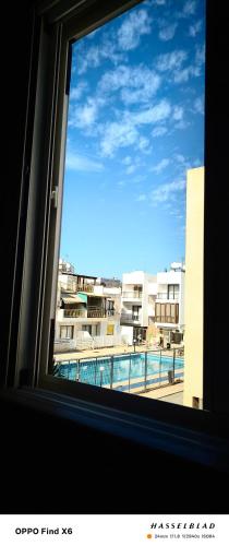 a window with a view of a pool and buildings at Siamese Villa in Paralimni
