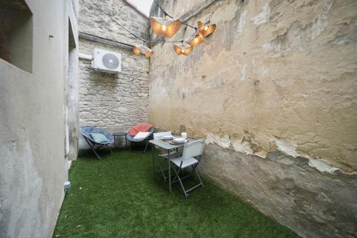 d'une terrasse avec 2 chaises et une table avec de l'herbe verte. dans l'établissement Wild Room Spa & cour privée au cœur de Montpellier, à Montpellier