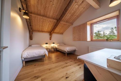 Cette chambre dispose de deux lits, d'une fenêtre et de plafonds en bois. dans l'établissement Elégante maison 225 m2, au Vert, 10 personnes, 5 chambres, 5 salles de bain, à Saint-Bonnet-le-Chastel