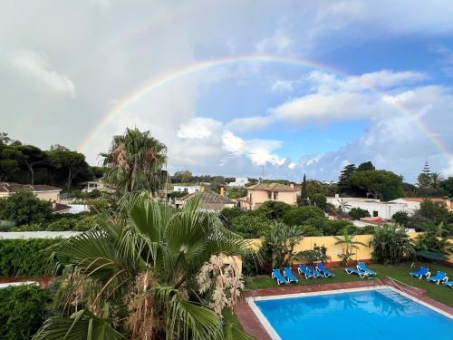 a rainbow over a swimming pool with chairs at Hotel Pinomar in El Puerto de Santa María